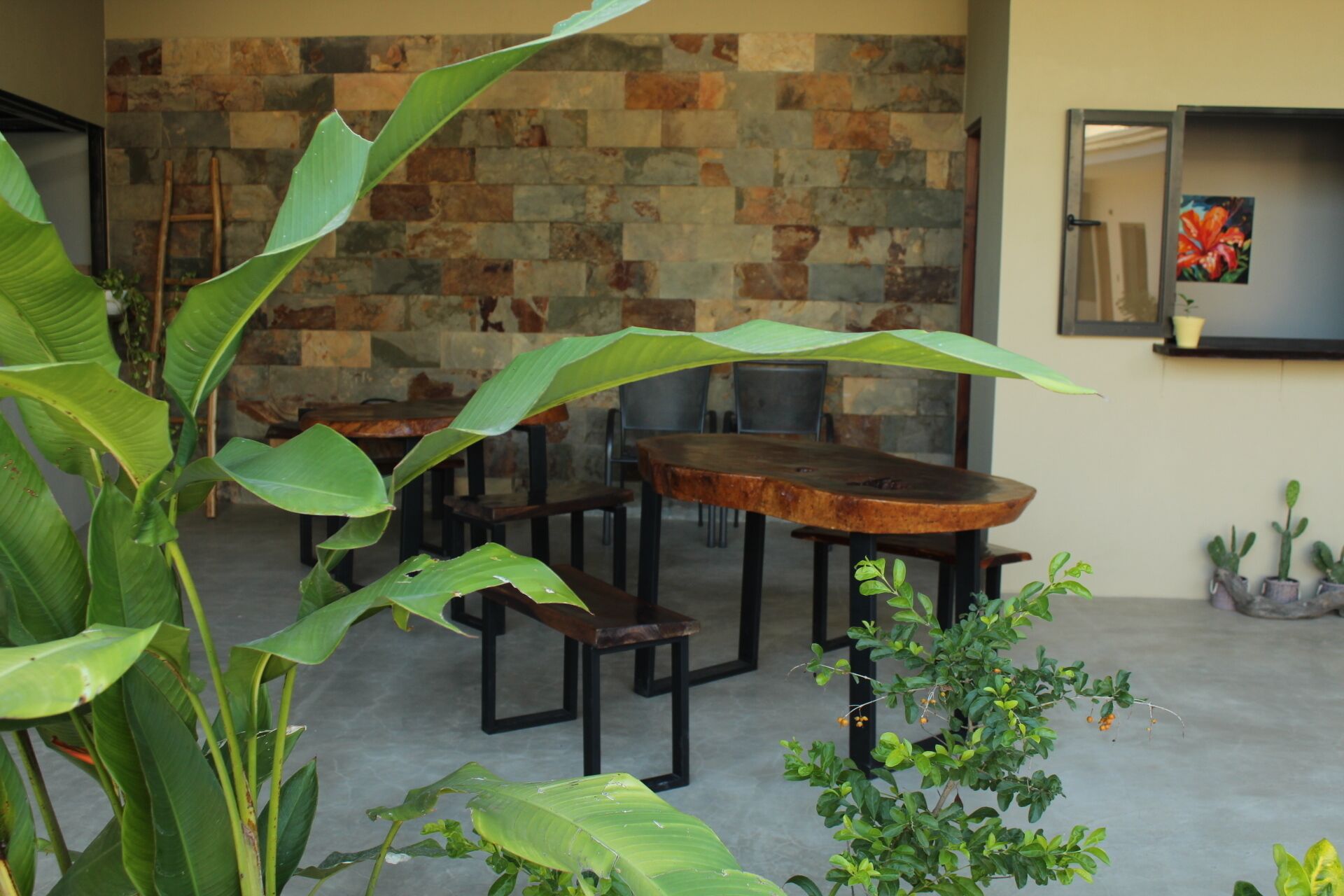 A dining area with a stone wall backdrop, wooden tables, and chairs.