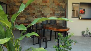 A dining area with a stone wall backdrop, wooden tables, and chairs.