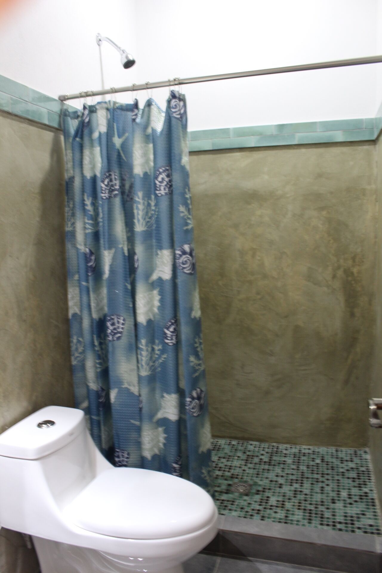 Een kleine badkamer met toilet, douchegordijn en betegelde vloer.