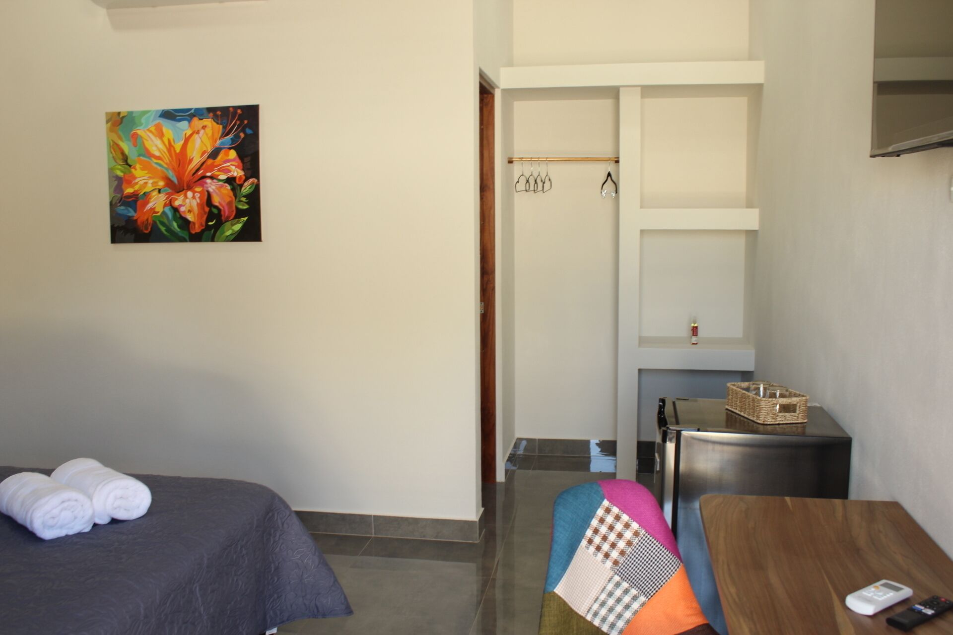 A hotel room with two beds, a painting, a small table, and a kitchenette.