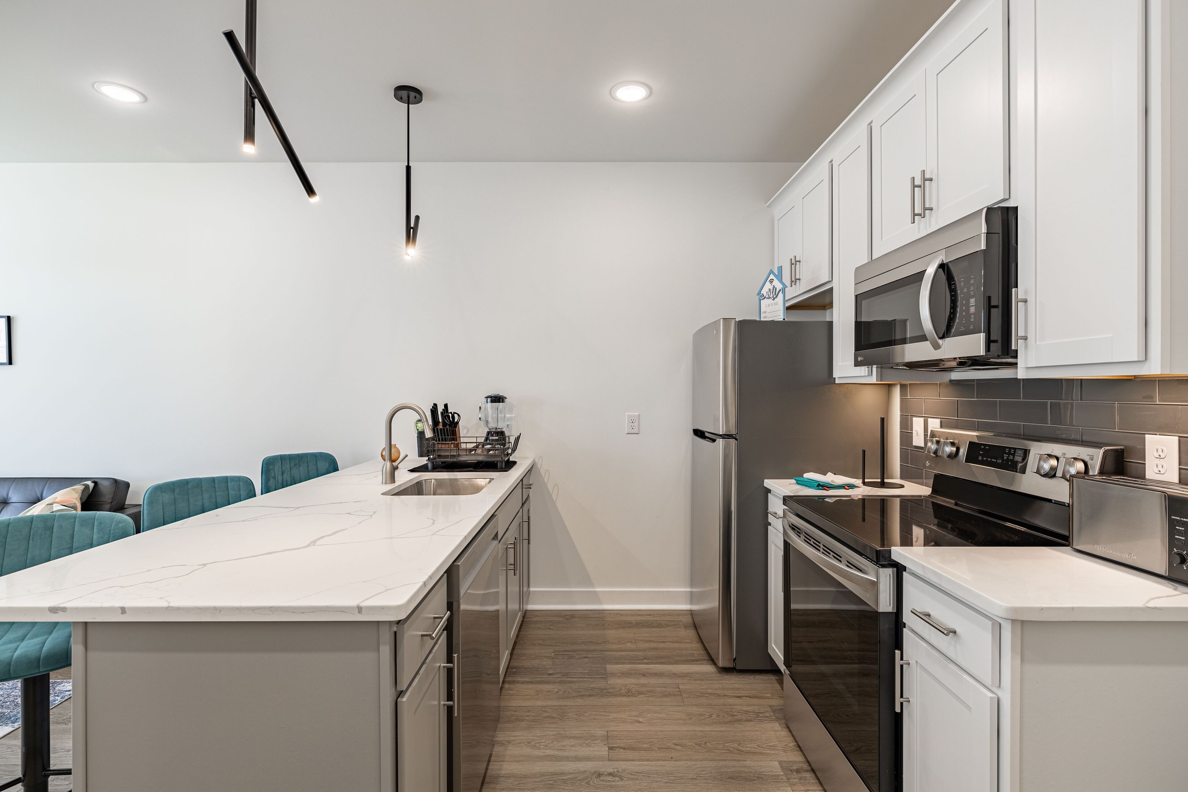 A modern kitchen with white cabinets, stainless steel appliances, and a marble countertop.