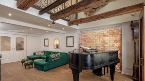 A spacious living room with a grand piano, a green sofa, and a stone wall. - Luxurious sandstone villa - 320 sqm - 7 rooms (Dresden)
