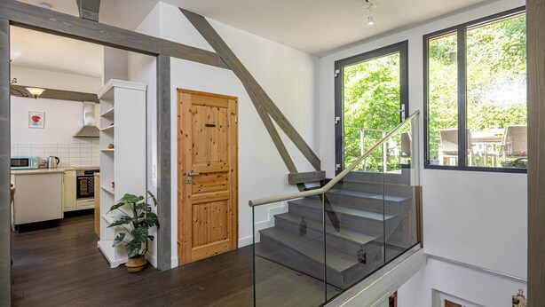 A staircase with glass railings leading to a second floor, a wooden door, and a view of a kitchen area with a plant. - Luxurious sandstone villa - 320 sqm - 7 rooms (Dresden)