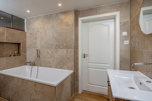 Een badkamer met een bad, een wastafel en een deur.