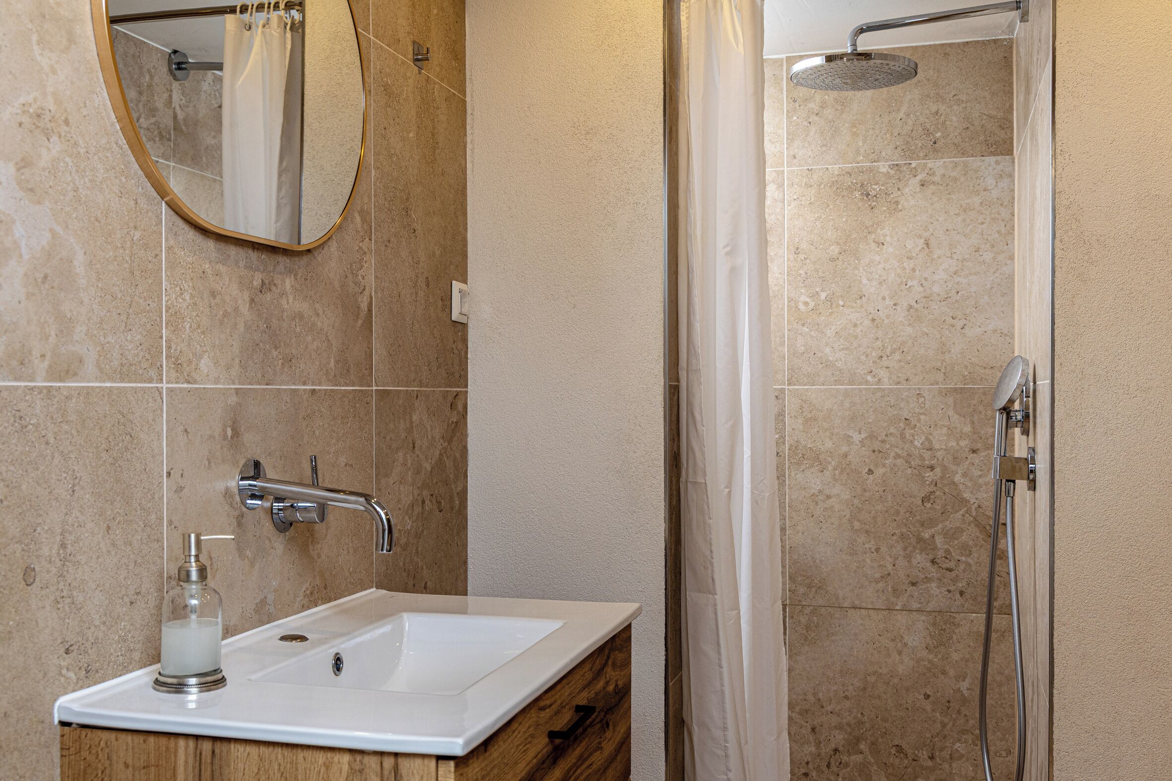 A bathroom with a sink, mirror, shower, and towel rack.