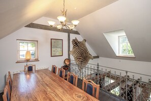 Un espace repas avec une longue table en bois, des chaises, un lustre et une sculpture de zèbre.