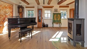 A spacious room with a grand piano, a wooden floor, a fireplace, and a large window allowing natural light. - Luxurious sandstone villa - 320 sqm - 7 rooms (Dresden)