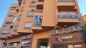 Un edificio de varios pisos con diseño moderno, que cuenta con balcones, unidades de aire acondicionado y un bar en la planta baja.