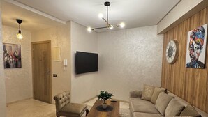 Una sala moderna con sofá, sillones, una mesa de centro y televisión.