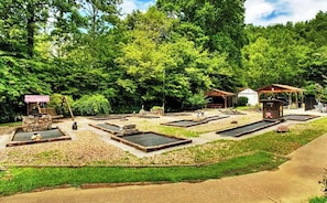 A garden with raised beds, a small structure, and a pathway. - Crofty Bear - RV Campsite in Gatlinburg - Free WiFi & Full Hookups in RV Resort (Gatlinburg)