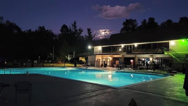 Une piscine au crépuscule, avec un bâtiment en arrière-plan.