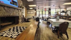 Un restaurant avec un mur en pierre, un sol à carreaux et des tables dressées pour le service.