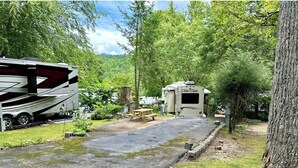 Un terrain de camping avec des emplacements pour camping-cars, une table de pique-nique et un chemin pavé menant à un chalet.