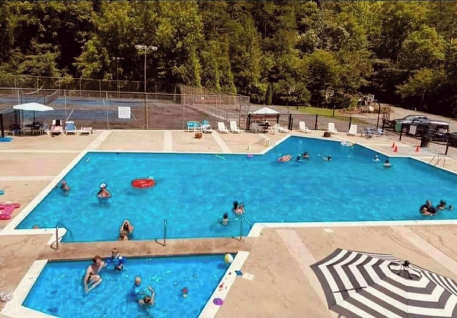 Ein Schwimmbecken mit mehreren Bahnen, umgeben von Liegestühlen und Sonnenschirmen.