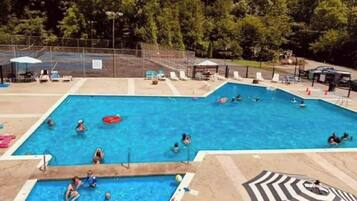Ein Schwimmbecken mit mehreren Bahnen, umgeben von Liegestühlen und Sonnenschirmen.