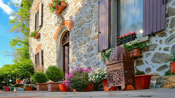 A stone building with multiple windows, some with shutters, and various potted plants and flowers around the exterior. - Nice home in Lamporecchio (Lamporecchio)