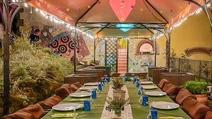 A long dining table set for a meal with a central floral arrangement, surrounded by cushioned seating. - Nice home in Lamporecchio (Lamporecchio)