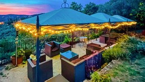 An outdoor patio with a covered seating area, string lights, and a view of the surrounding landscape. - Nice home in Lamporecchio (Lamporecchio)