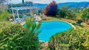 A swimming pool surrounded by lush greenery and a pergola with seating. - Nice home in Lamporecchio (Lamporecchio)