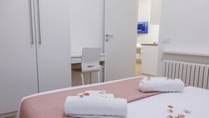 Hotellihuone, jossa on sänky, työpöytä ja tuoli.