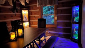 A cozy cabin interior with a wooden dining table, benches, and a bench seat. A window with a view of greenery is visible. - Big Kahuna Mauka, Beautiful Mountain View 4-BR Cabin in charming Waynesville (Waynesville)