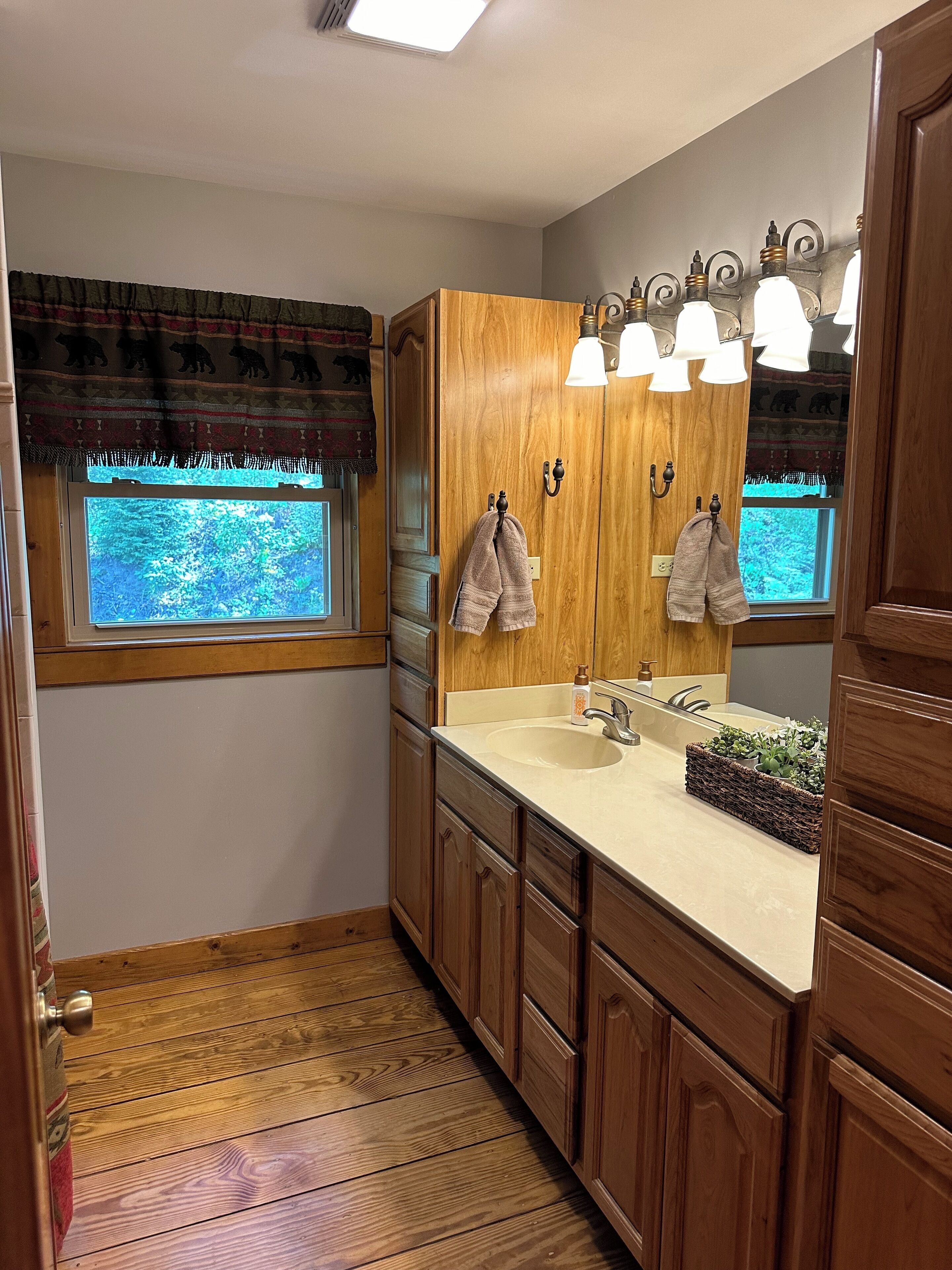 A wooden bathroom with a window, a sink, and a mirror.