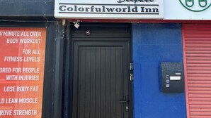 A storefront with a sign for 'Colorfulworld Inn' featuring a logo with a pink flower and a mountain.