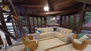 A cozy room with a large sectional sofa, wicker chairs, and a wooden staircase. - Refugio Do Frances Ghesthouse (São Sebastião)