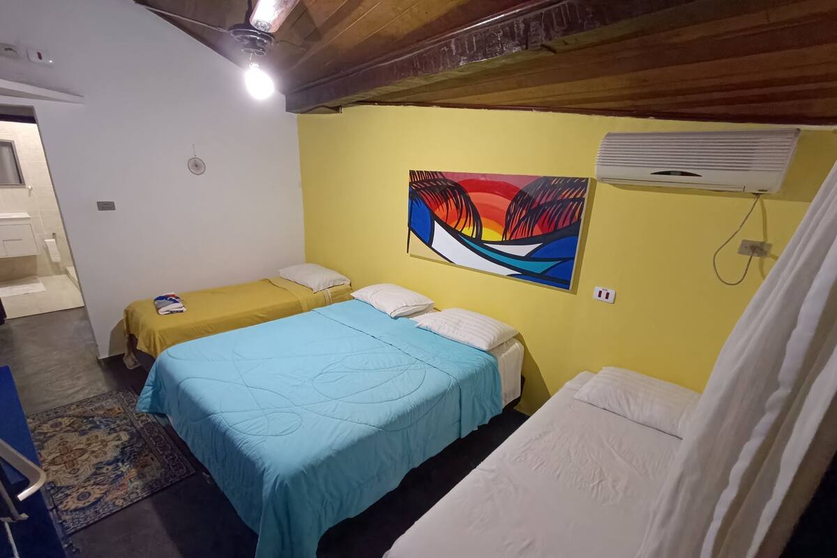 A room with two single beds, a large abstract painting on the wall, and an air conditioning unit.