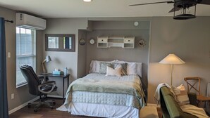 Un dormitorio con cama, escritorio, silla y ventilador de techo.