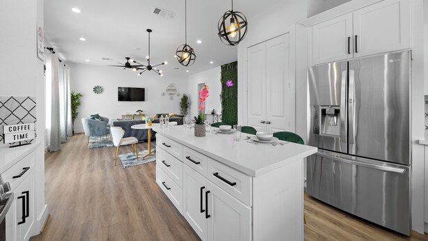 Een moderne keuken met witte kastjes, een roestvrijstalen koelkast en een centraal eiland met een spoelbak.