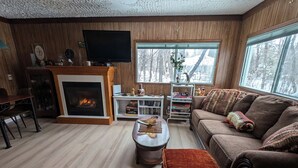 Ein gemütliches Wohnzimmer mit Kamin, einer Couch, einem Couchtisch und einem Fernseher.