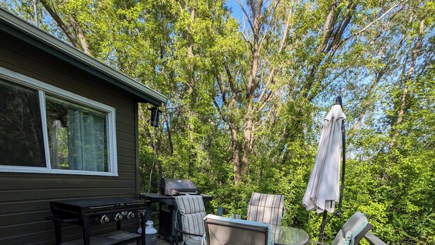 Eine Holzterrasse mit Gartenmöbeln, einem Grill und einem überdachten Bereich.