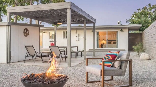 An outdoor patio with a fire pit, seating, and a covered area.