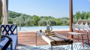 A wooden deck with a table set for a meal, overlooking a pool and lush greenery. - Cozy home in Cortoreggio- AR with sauna (Cortoreggio- AR)