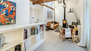 A modern living room with exposed wooden beams, a fireplace, a sofa, and a bookshelf. - The B Hive at Buckstone House (Carnforth)