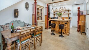 A spacious kitchen with a wooden island, bar stools, and a dining table with chairs. - The B Hive at Buckstone House (Carnforth)