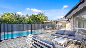 A wooden deck with a pool, outdoor seating, and a covered patio area. - Black Shack Burleigh (Burleigh Waters)