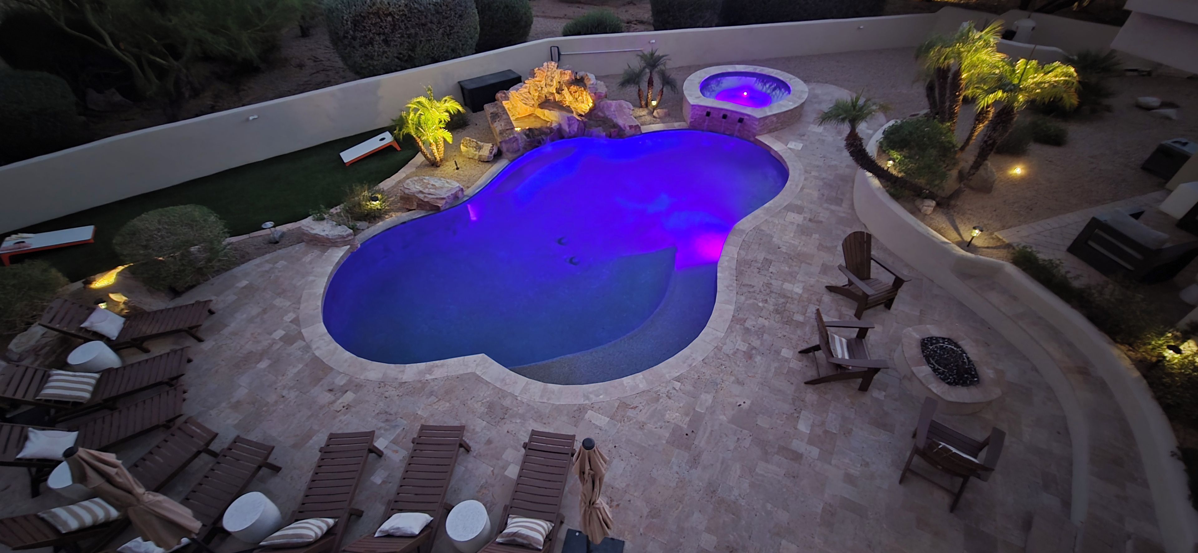 A swimming pool with lounge chairs and a hot tub area.