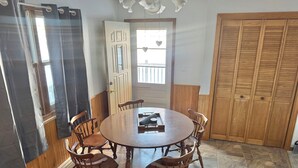 A dining area with a round wooden table and six chairs, a wooden door with a heart-shaped decoration, and a wooden wardrobe. - Private Lakeside Escape on Devils Lake  (Devils Lake)