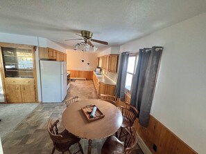 A kitchen with wooden cabinets, a white refrigerator, a dining table with chairs, and a ceiling fan. - Private Lakeside Escape on Devils Lake  (Devils Lake)