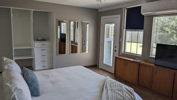 A bedroom with a bed, a wardrobe, a mirror, and a window. - Cozy B- condo in charming Corpus Christi with WiFi, AC near Laguna Madre (Corpus Christi)