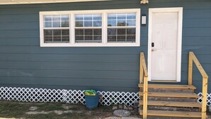 A house with a dark blue exterior, a white door, and a set of wooden steps leading to the door. - Cozy B- condo in charming Corpus Christi with WiFi, AC near Laguna Madre (Corpus Christi)