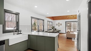 A modern kitchen with a large island, wooden ceiling, and large windows. - Cozy 4-Bedroom Modern Mountaintop Retreat in Jewett  (Jewett)