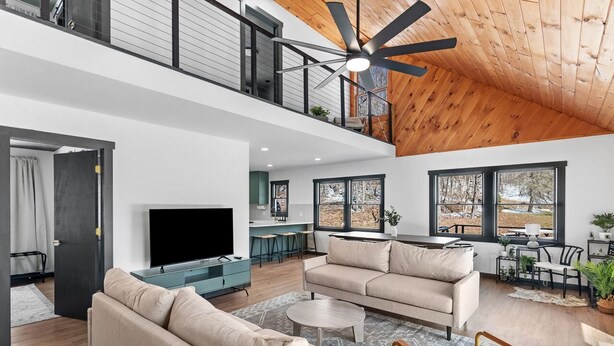 A spacious living area with a large TV, a sofa, and a dining table. - Cozy 4-Bedroom Modern Mountaintop Retreat in Jewett  (Jewett)