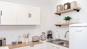 A modern kitchen with white cabinets, a wooden countertop, a coffee maker, a toaster, and a sink. - Spacious Studio Retreat (Phoenix)