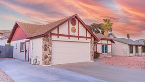 A two-story house with a garage, stone pillars, and a red roof. - Spacious Studio Retreat (Phoenix)