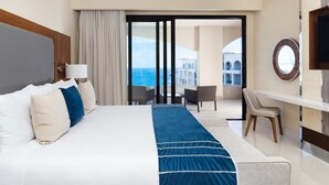 Habitación de hotel con una cama grande, un escritorio, una silla y vista al mar.