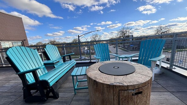 Terraza en la azotea con mobiliario exterior, que incluye una mesa redonda y sillas, y vistas de la ciudad.