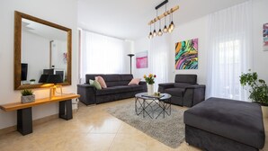 A modern living room with a sofa, armchair, coffee table, and a large mirror. - Amazing home in Lucane (Lucane)